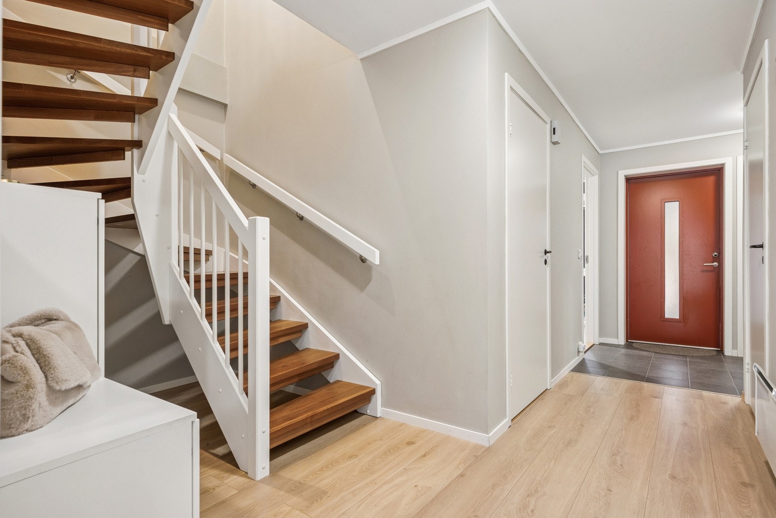 Glassfelt i ytterdøra sørger for en lys og trivelig entré med gang. Vi tar turen opp i boligens hovedoppholdsrom! Galleribilde