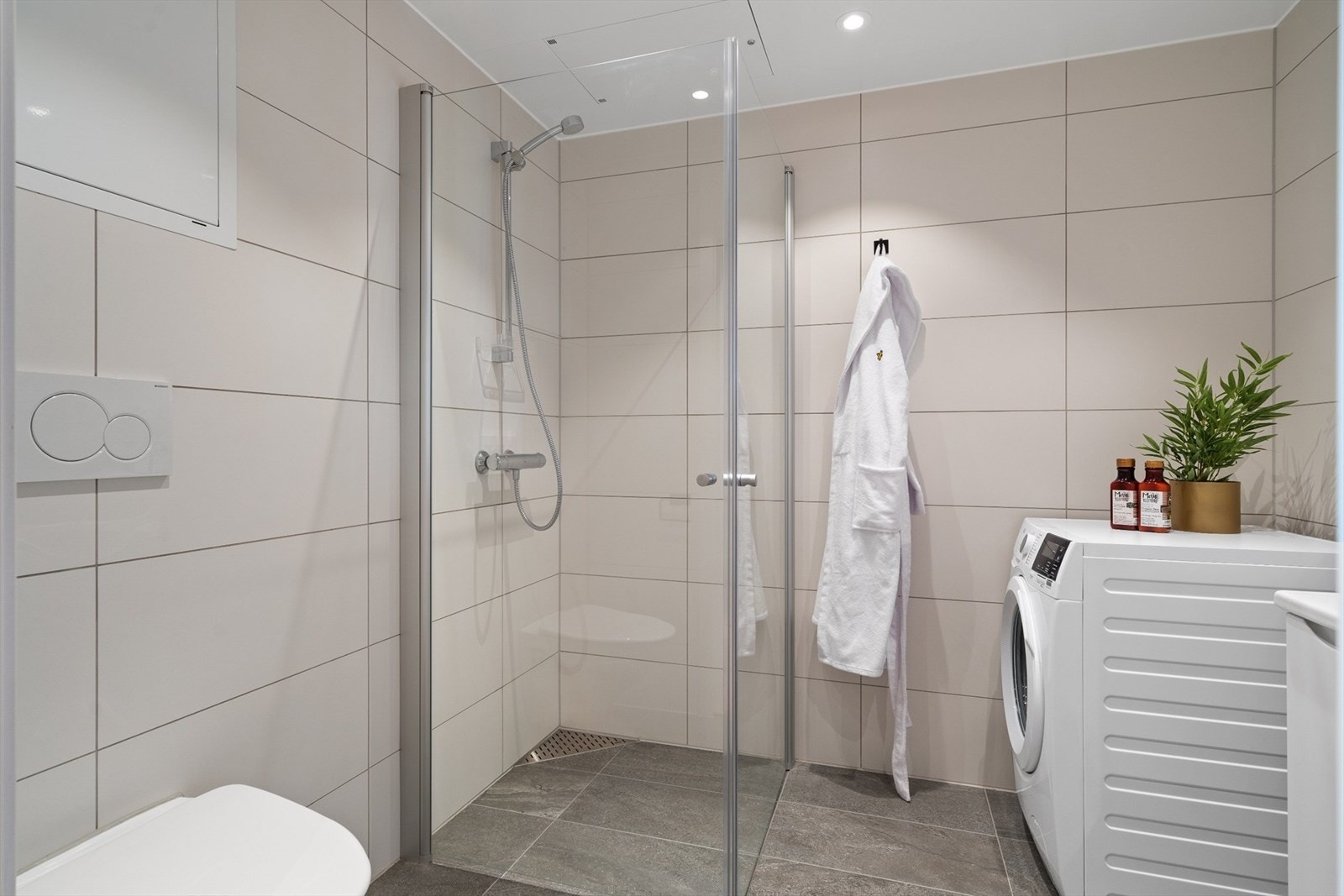 Badet er utstyrt med servant, servantskap, opplegg for vaskemaskin, innfellbare dusjdører, veggmontert wc og rørfordelingsskap. Galleribilde