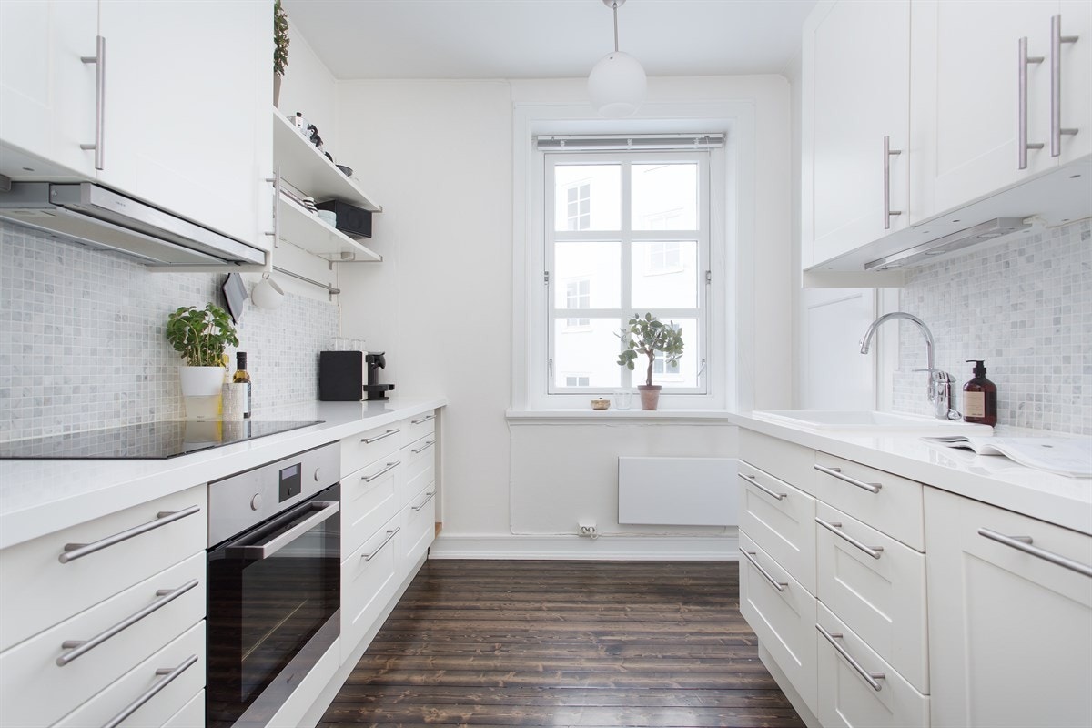 Lyst kjøkken med integrerte hvitevarer. Det er balkong i dag der vinduet er på bilde. Galleribilde