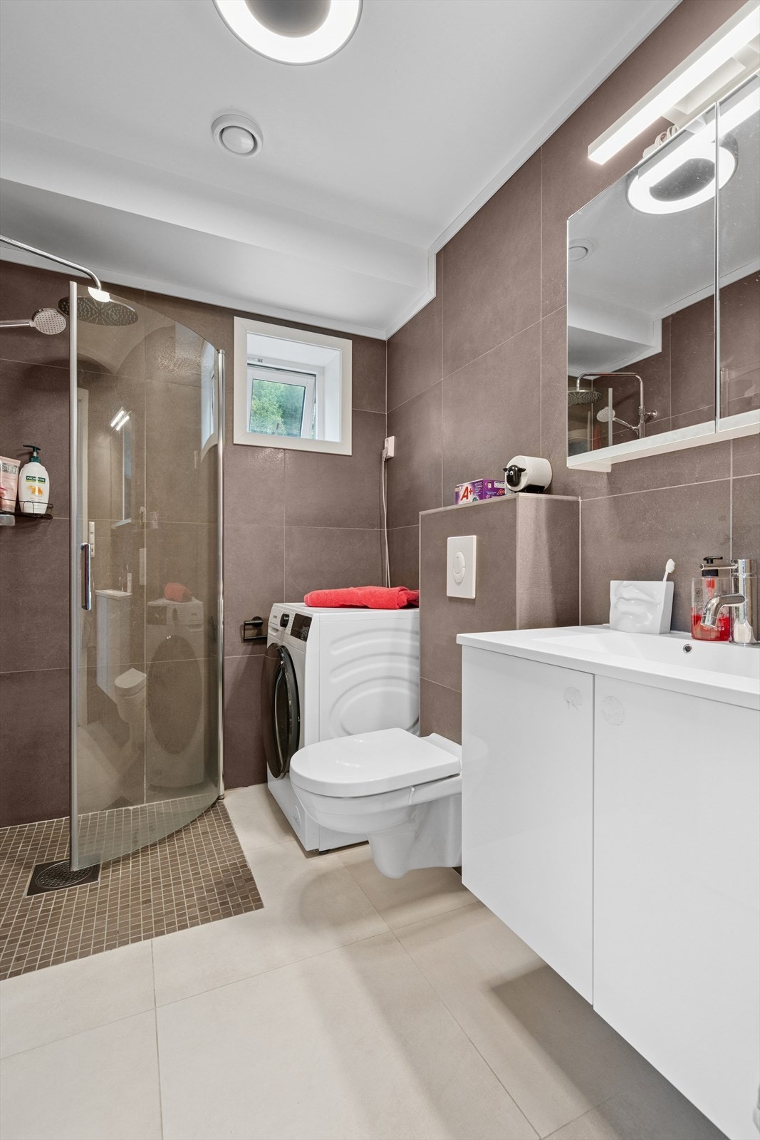 HYBEL: Badet har flislagte overflater - Her finner du vegghengt toalett, dusjnisje m/innfellbare glassdører, baderomsinnredning og opplegg for vaskemaskin Galleribilde