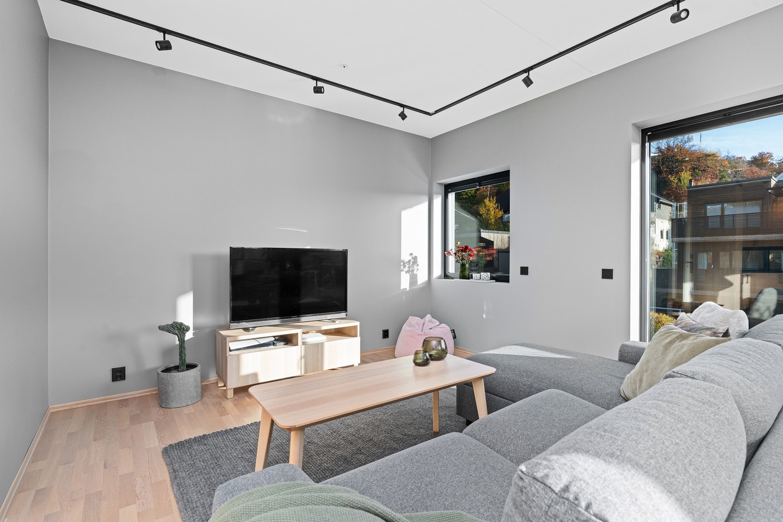 Gjennomført stue med enkle linjer og duse fargevalg, skjermet med persienner Galleribilde