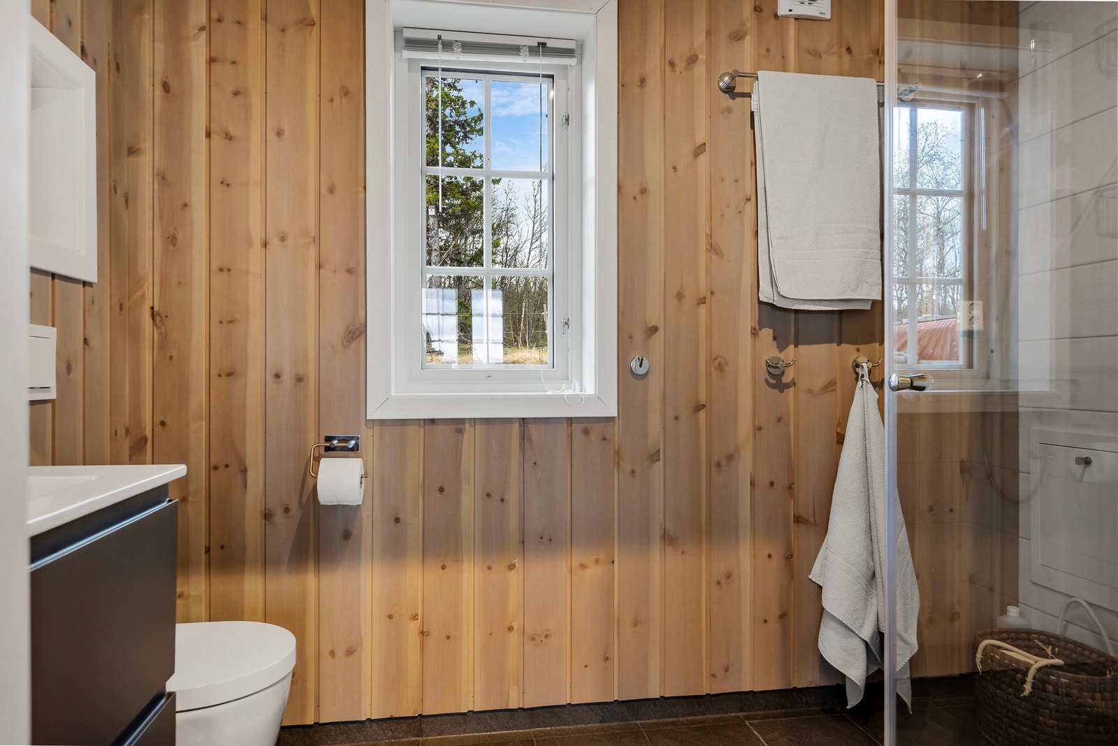 Bad/vaskerom har servant, vegghengt klosett, opplegg til vaskemaskin og dusj med glassvegger. Galleribilde