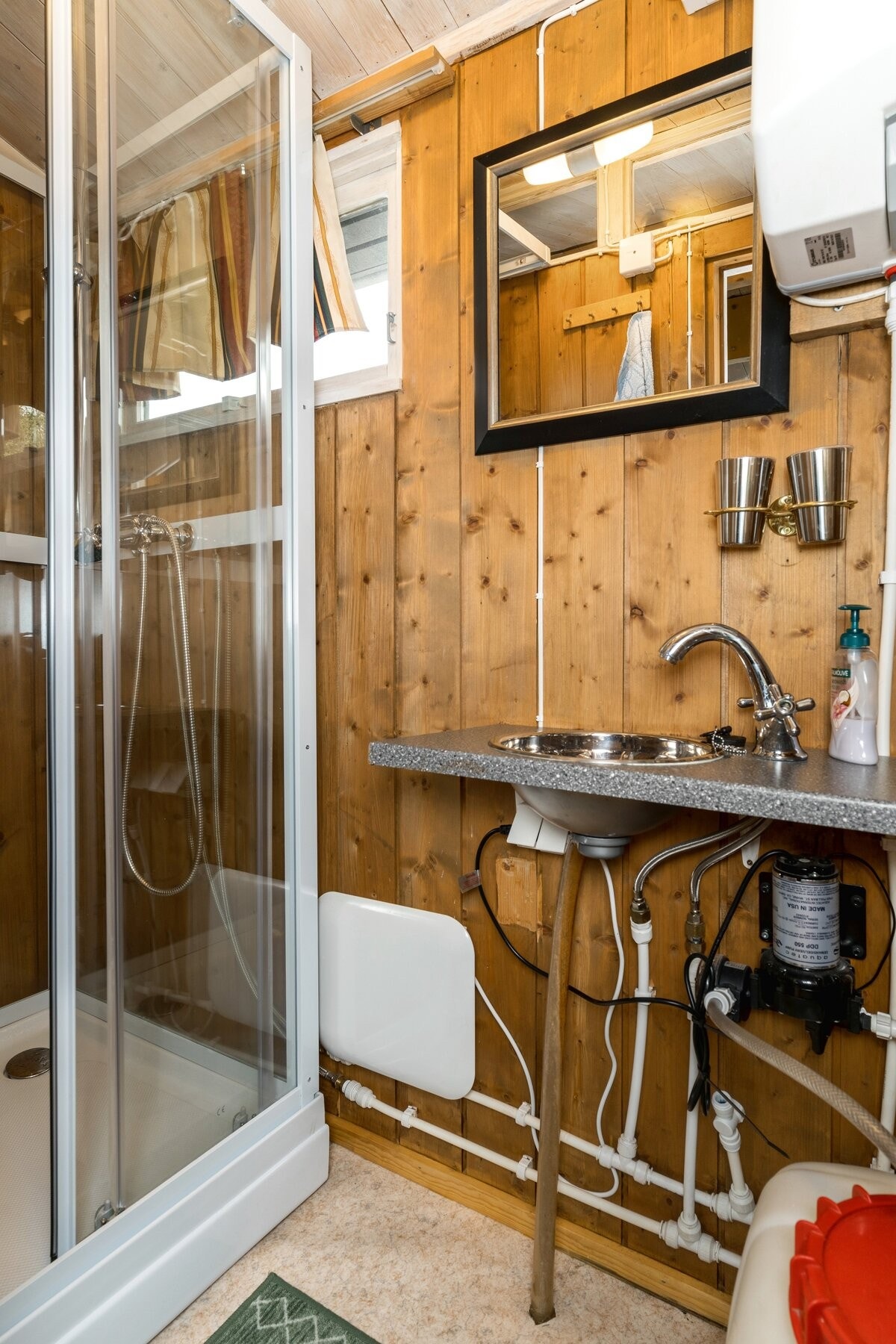 Enkelt hyttebad innredet med dusjkabinett og vask tilkoblet Vera vannsystem. Galleribilde