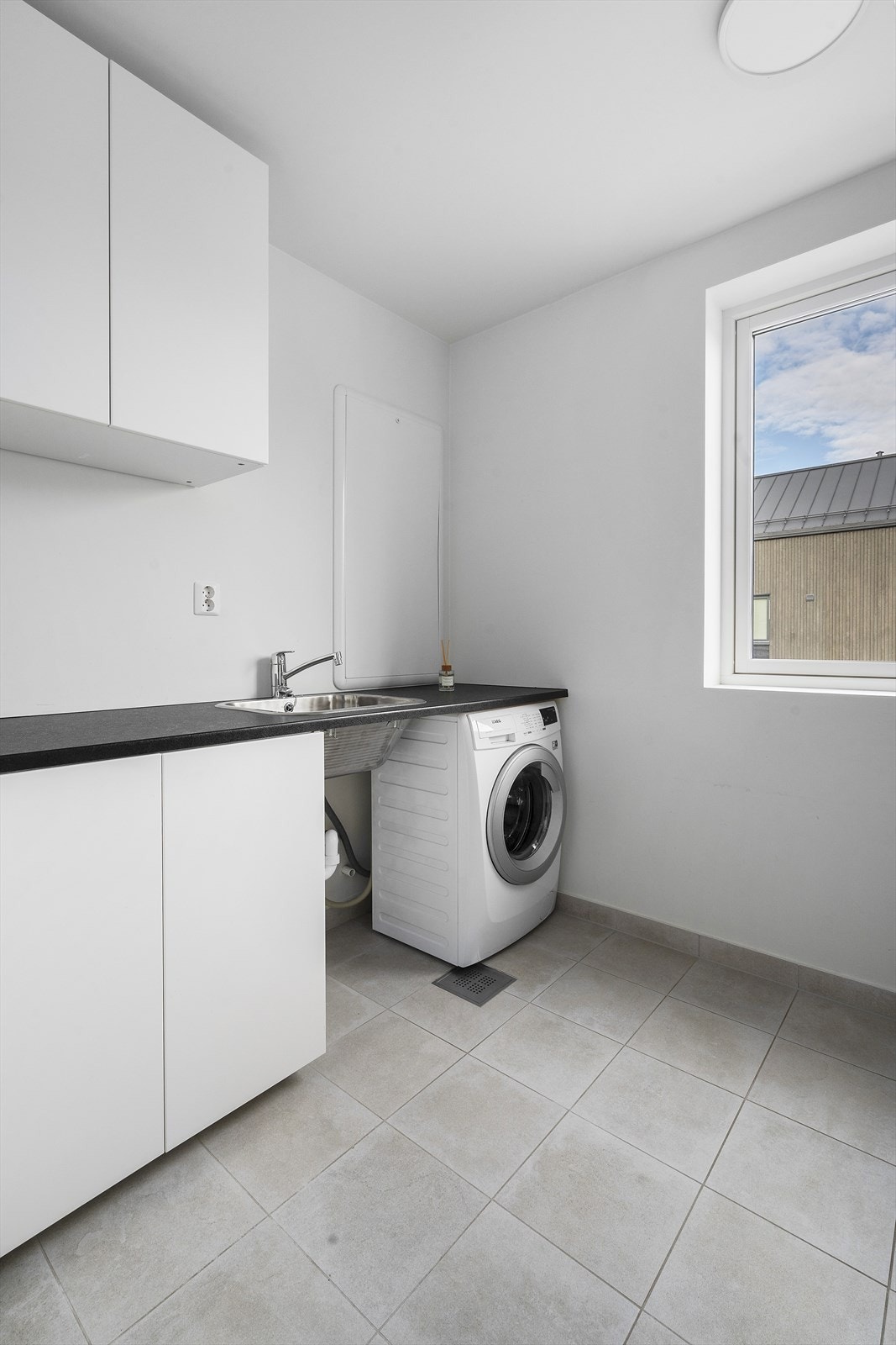 Vaskerommet har benkeplate med skylle kum og opplegg for vaskemaskin. Galleribilde