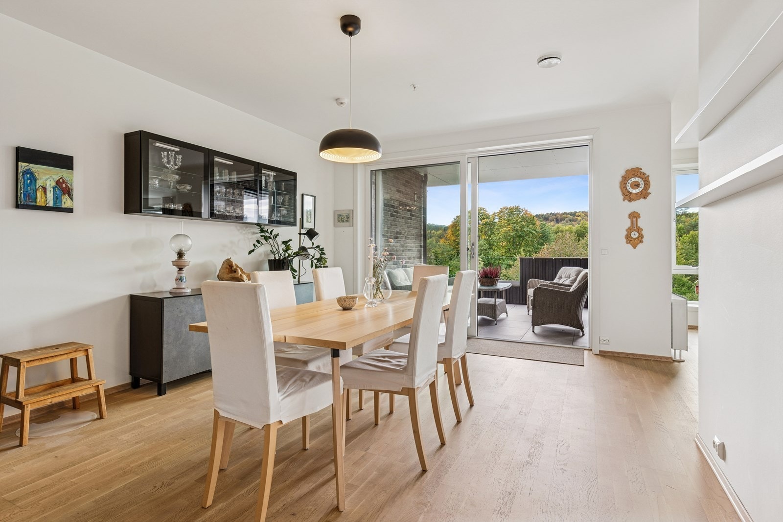 Lys og innbydende spisestue med store vinduer som åpner opp mot en naturskjønn utsikt og romslig balkong. Galleribilde