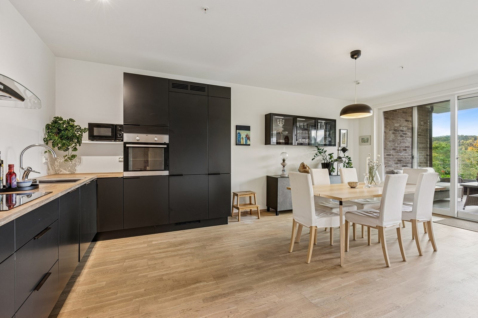 Lys og romslig stue med store vinduer og utsikt mot frodige, grønne omgivelser. Perfekt for avslappende stunder hjemme. Galleribilde