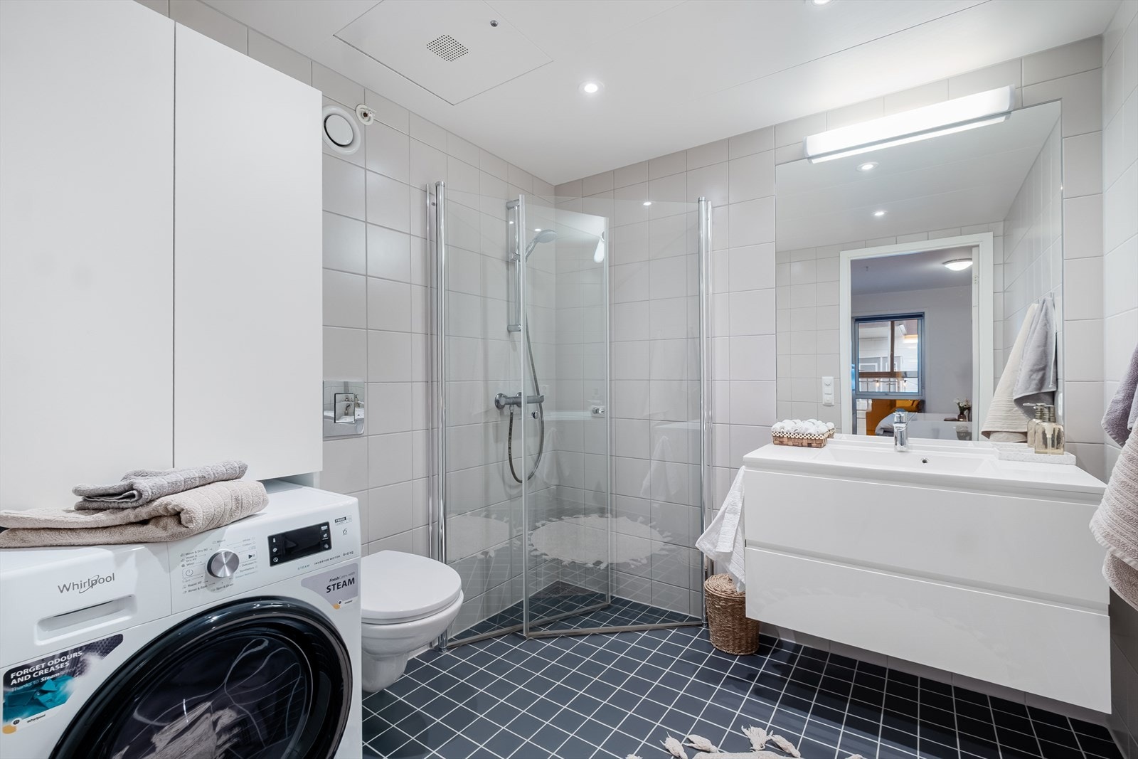 Pen flislagt bad utstyrt med dusjhjørne, vegghengt toalett og en moderne baderomsinnredning. Galleribilde