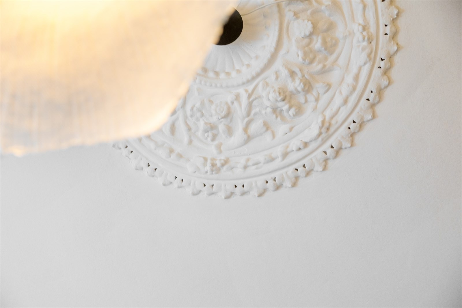 Rommet har et elegant preg med vakre, klassiske detaljer som rosett og stukkatur i himlingen, noe som gir en lun og tidløs atmosfære. Galleribilde