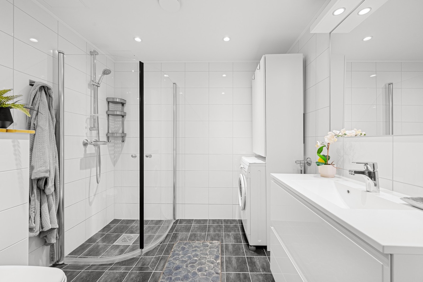 Stilrent baderom med flislagte gulv- og veggflater som gir et tidløst uttrykk. Galleribilde