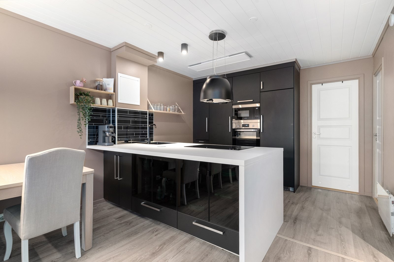 Pen, takhøy kjøkkeninnredning type Ikea fra 2020. Innredningen består av en egen seksjon med høyskap og praktisk kjøkkenøy ut mot stuen. Galleribilde