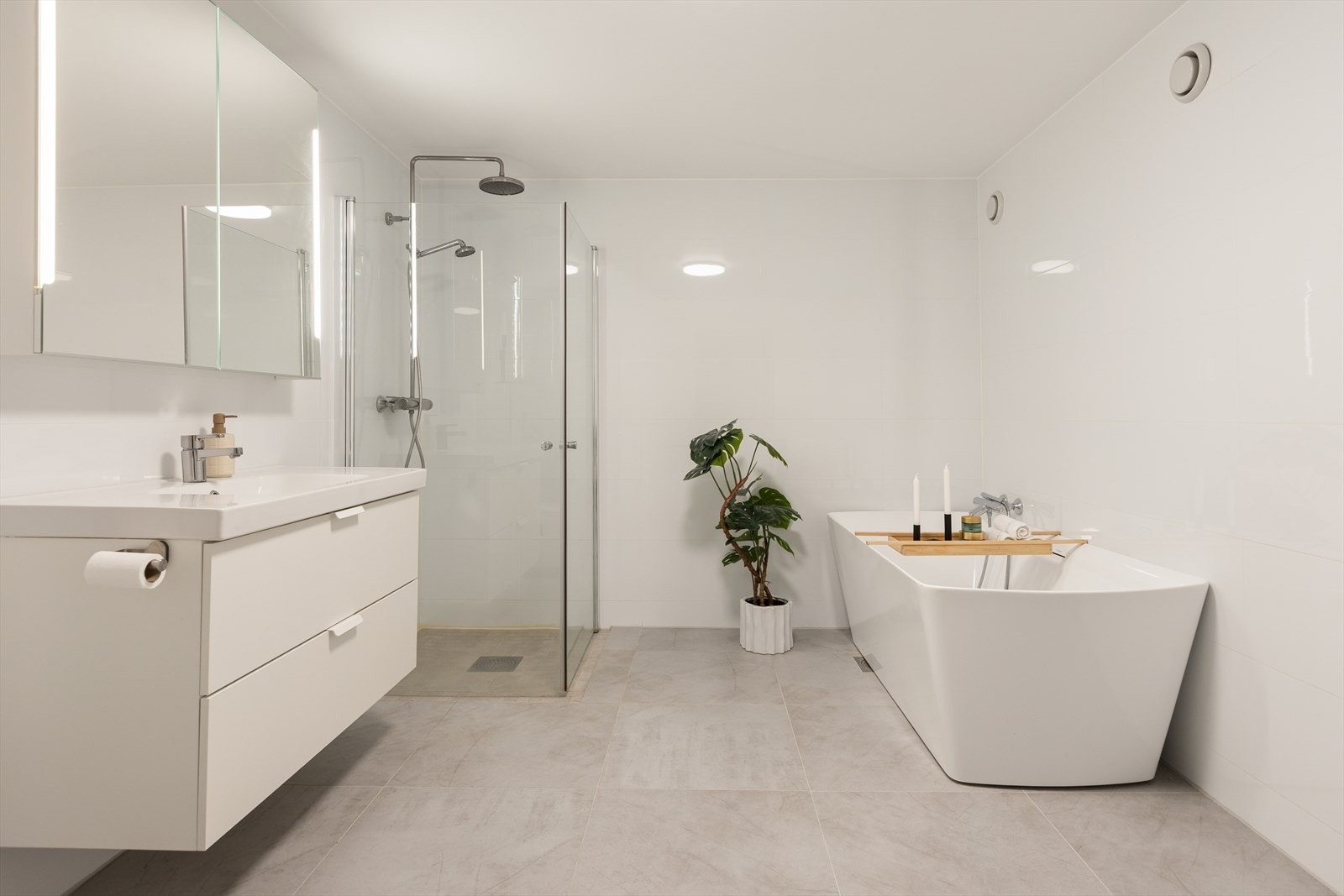 Innredningen består av en heldekkende servant med underskap, speil med belysning, vegghengt toalett og et dusjkabinett. Galleribilde