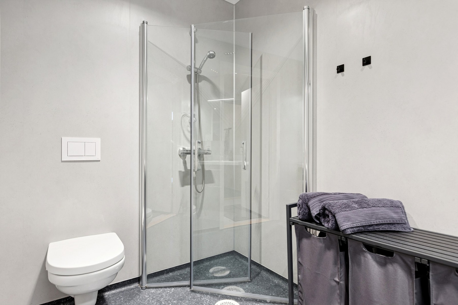 Badet er innredet med servantskap, innfellbare dusjdører, veggmontert wc, opplegg for vaskemaskin og mekanisk avtrekk. Galleribilde