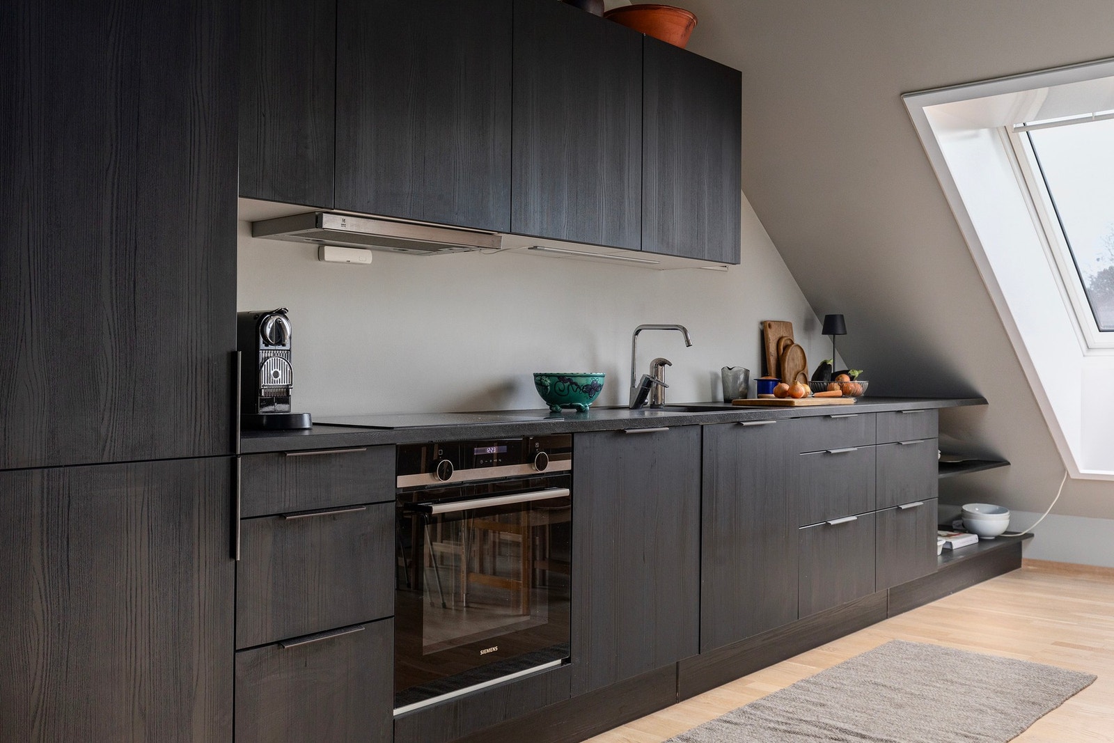 Av utstyr finnes kombinert kjøl- og fryseskap, stekeovn, koketopp, ventilator og oppvaskmaskin. Maksimal utnyttelse av plassen - med plassbygde hyller lengst inn mot skråtaket. Galleribilde