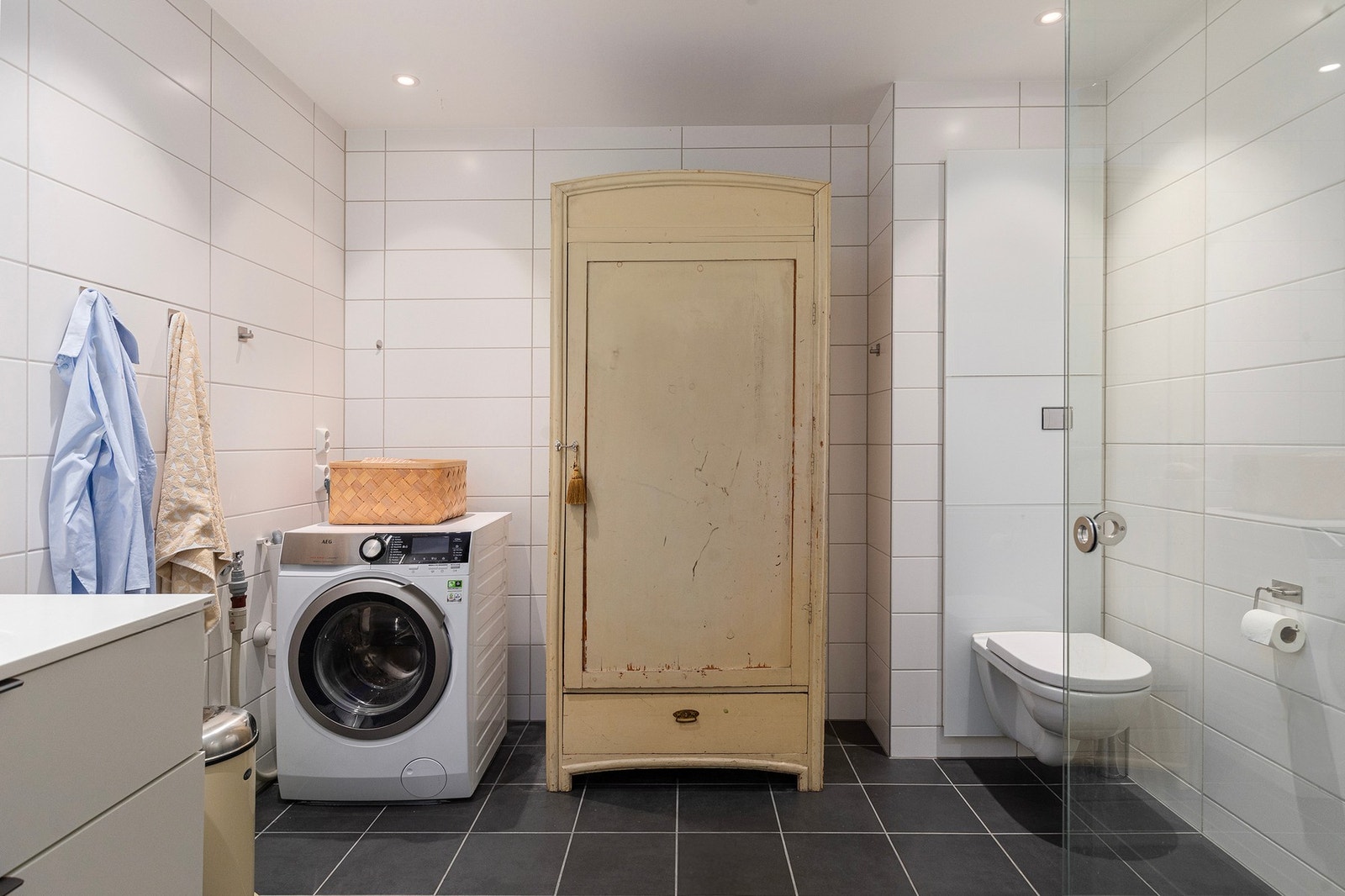 Flislagt og pent bad. Her har man opplegg for vaskemaskin, dusjnisje, vegghengt toalett, servant med skuffer og speil. Galleribilde