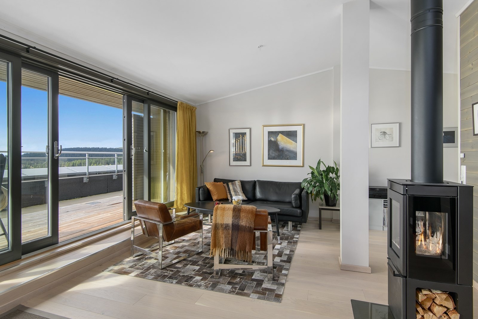 Stue med vedovn og store vinduer som gir rikelig med naturlig lys. Galleribilde