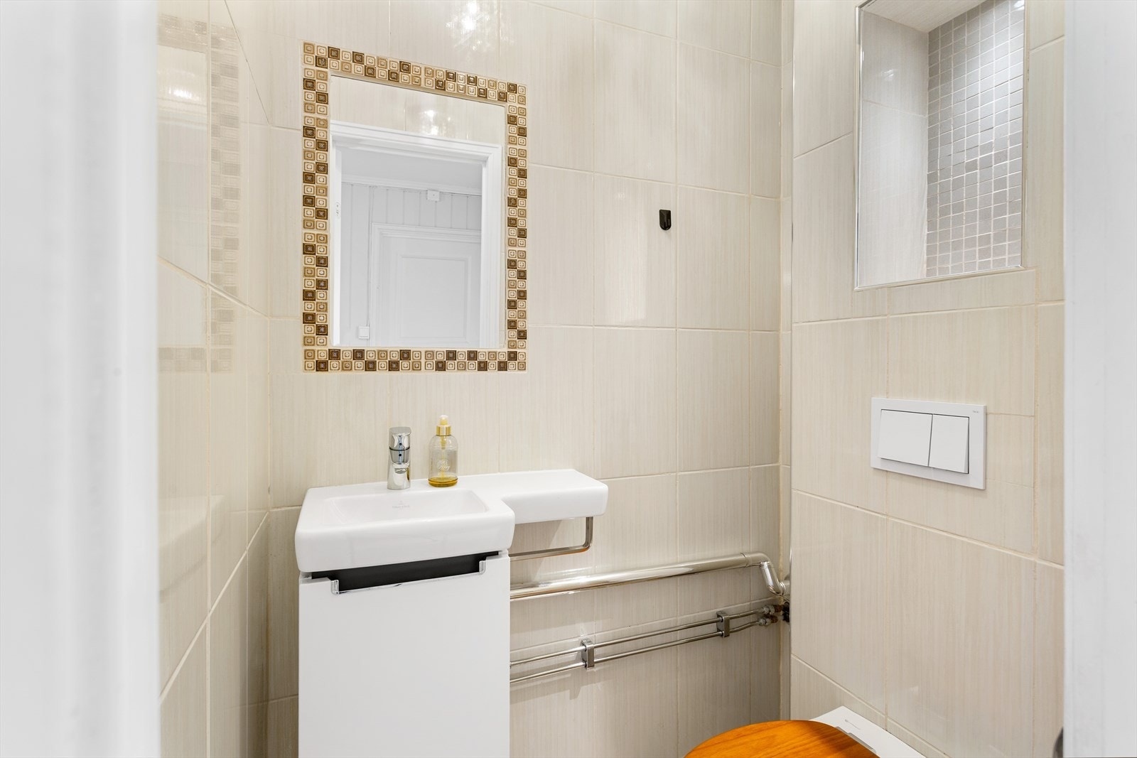 Flislagt toalettrom med en liten praktisk vask. Galleribilde