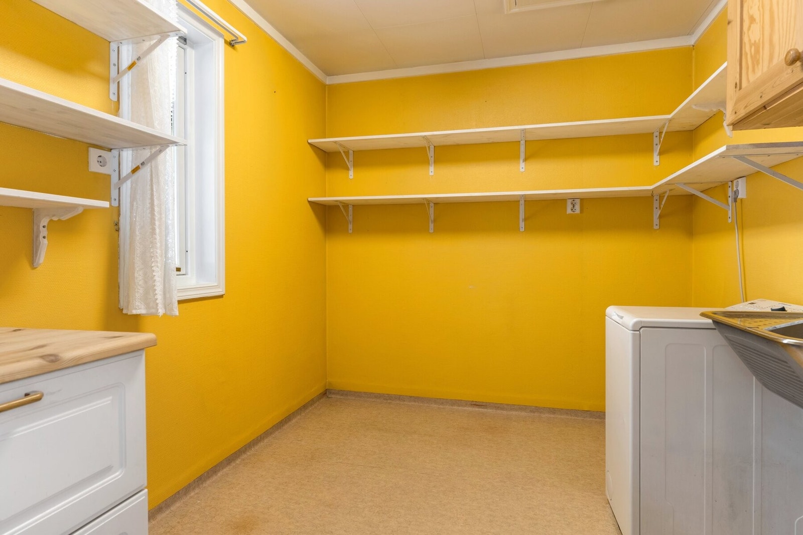 Praktisk vaskerom i tilknytning til kjøkkenet innredet med utslagsvask og opplegg for vaskemaskin. Galleribilde