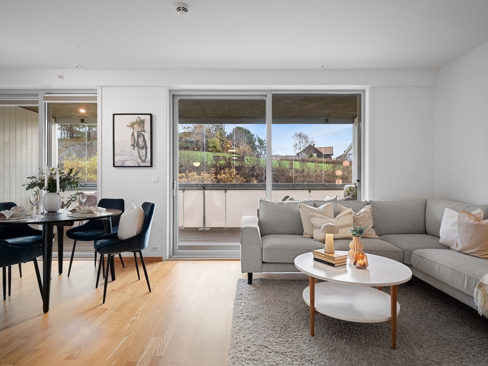 Lys og moderne stue med store vinduer og utgang til romslig balkong med utsikt mot grønne omgivelser. Galleribilde