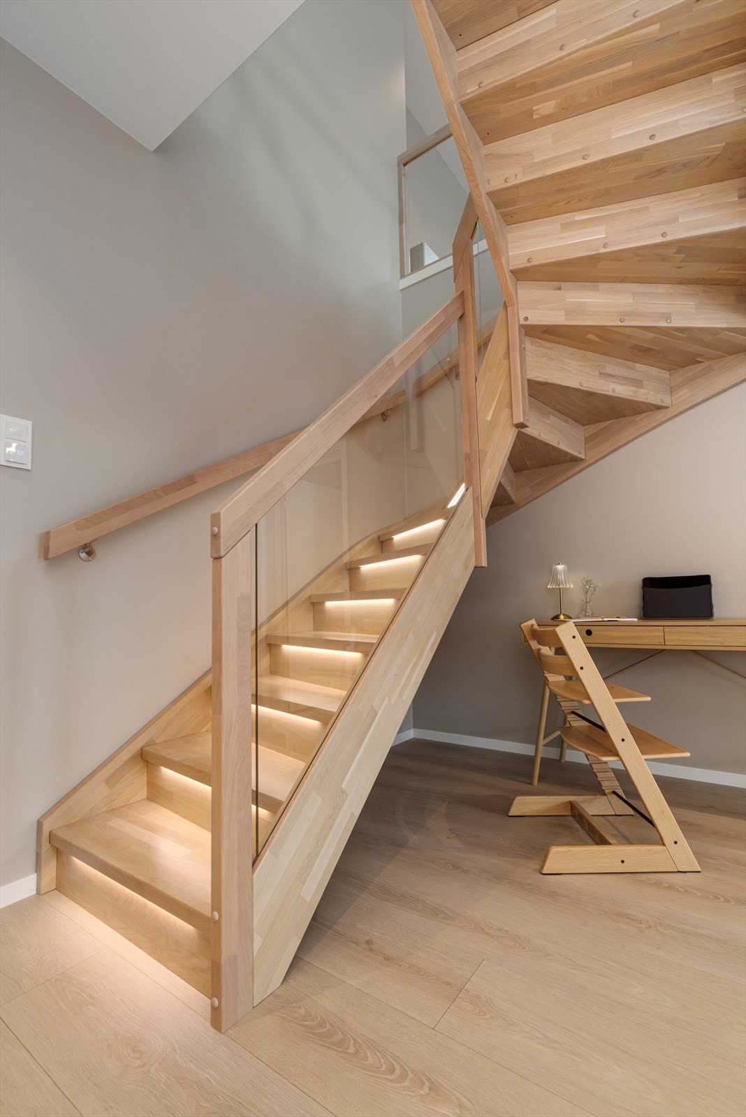 Trapp til underetasje i eik med integrert belysning og glassrekkverk. Galleribilde