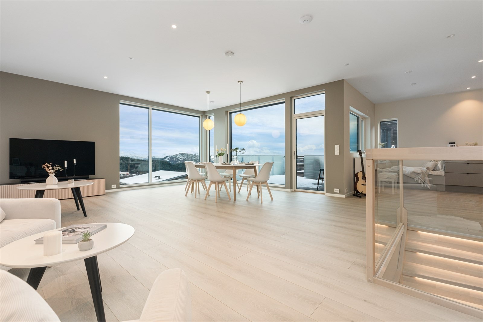 Stue med åpen løsning mot kjøkken med 270 cm takhøyde og store vindusflater. Rommet føles lyst og innbydende Galleribilde