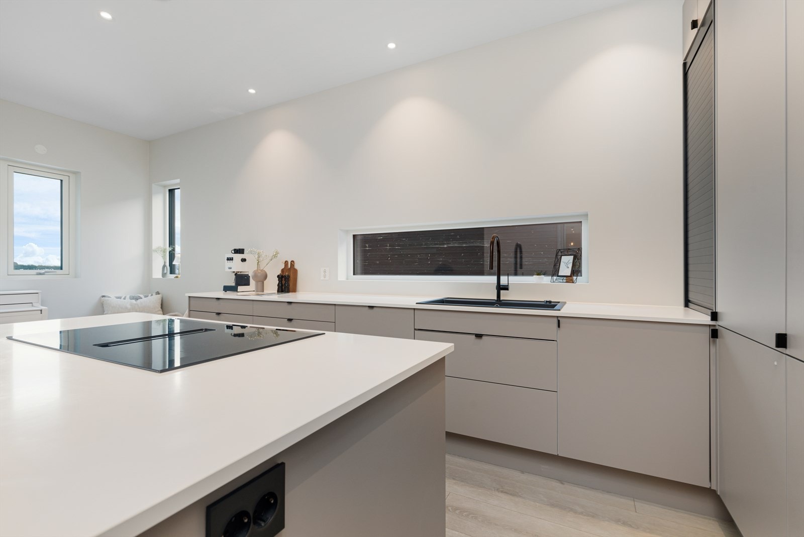 Gjennomført og påkostet kjøkken med moderne, slette fronter, god skapplass, kjøkkenøy med stor platetopp, nedfelt ventilator, integrerte hvitevarer med wifi-styring og integrerte Sonos-høyttalere i himlingen. Galleribilde