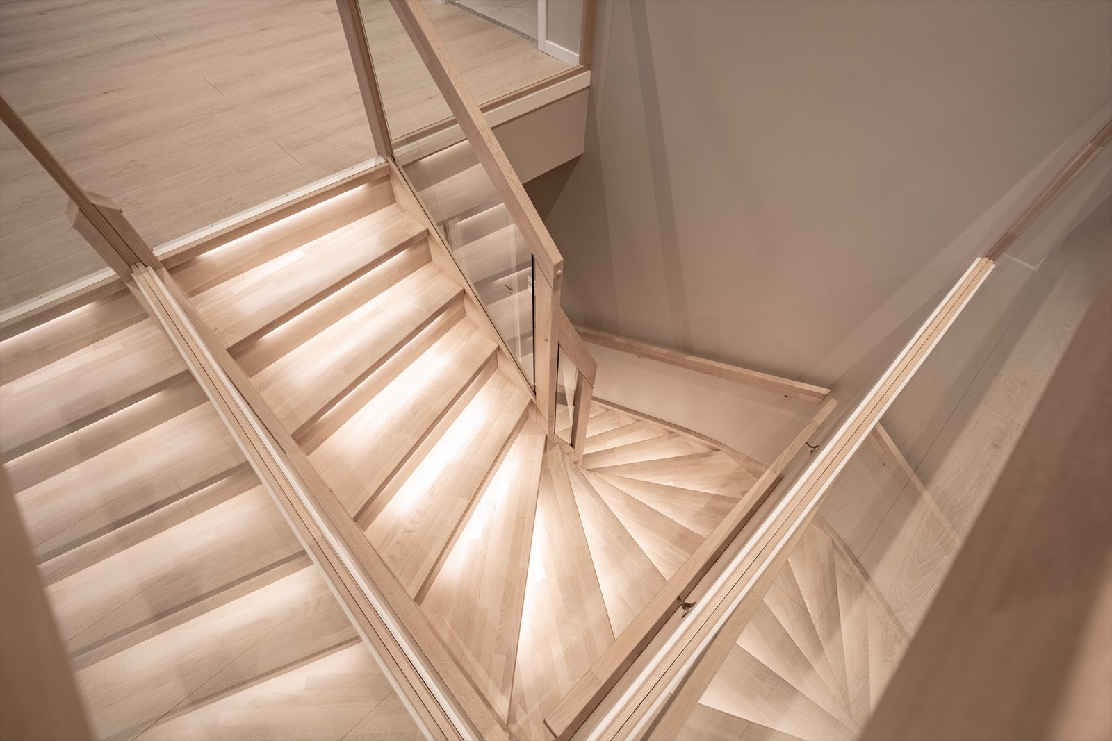 Trapp til underetasje i eik med integrert belysning og glassrekkverk. Galleribilde