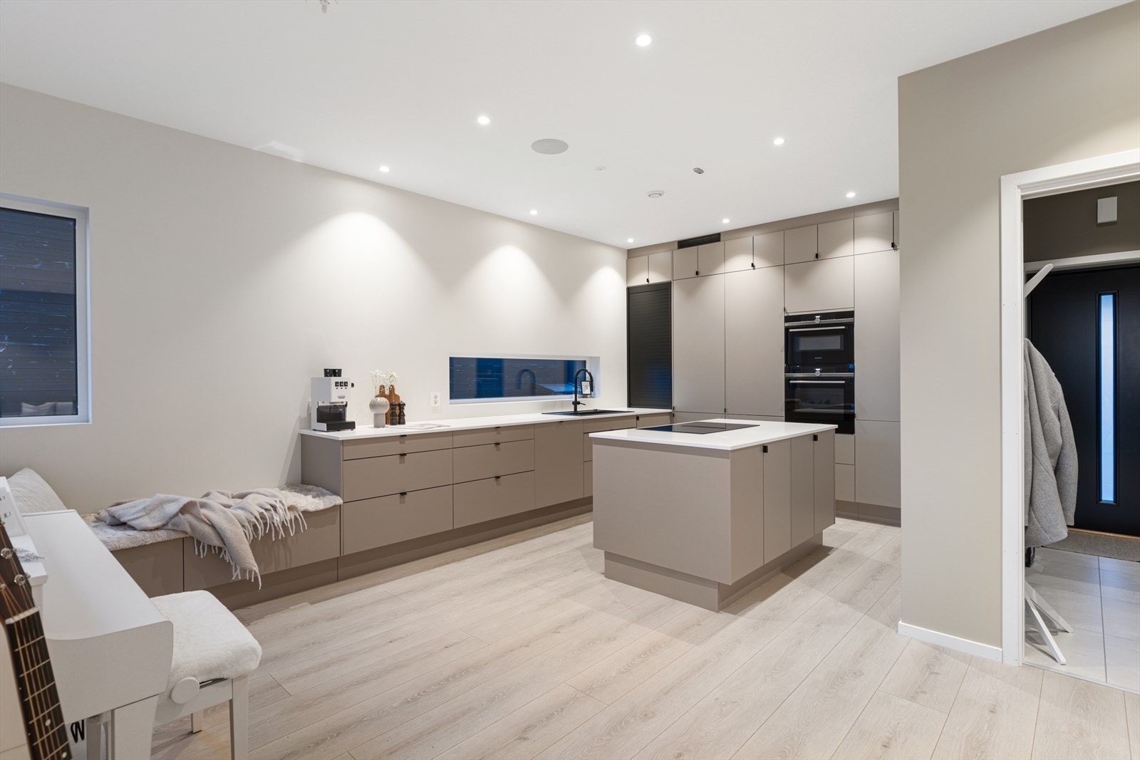 Gjennomført og påkostet kjøkken med moderne, slette fronter, god skapplass, kjøkkenøy med stor platetopp, nedfelt ventilator, integrerte hvitevarer med wifi-styring og integrerte Sonos-høyttalere i himlingen. Galleribilde