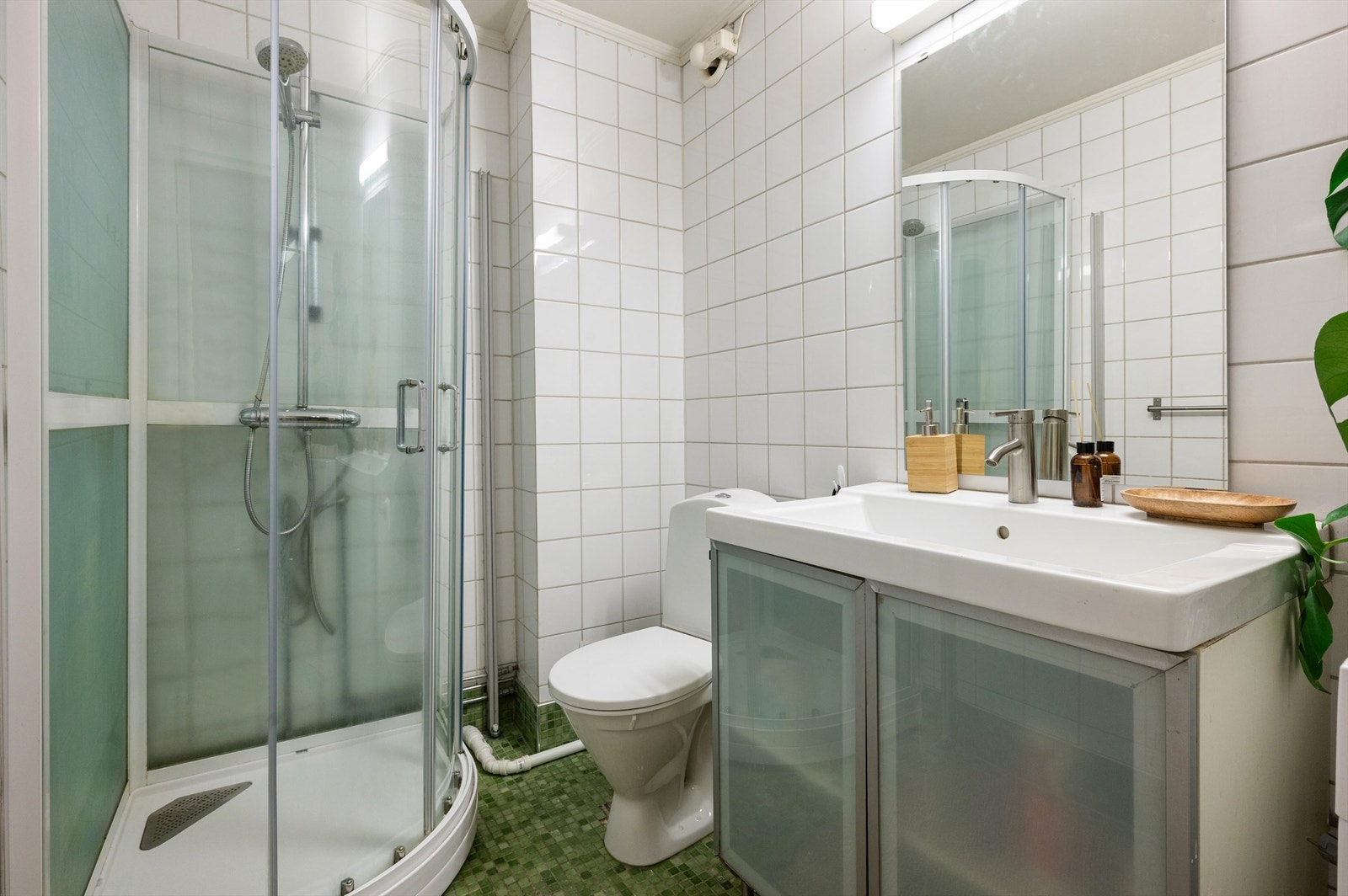 Rommet er innredet med gulvstående klosett, baderomsinnredning med heldekkende servant, speil og et dusjkabinett. Det er opplegg for vaskemaskin og en elektrisk styrt vifte for ventilasjon. Galleribilde