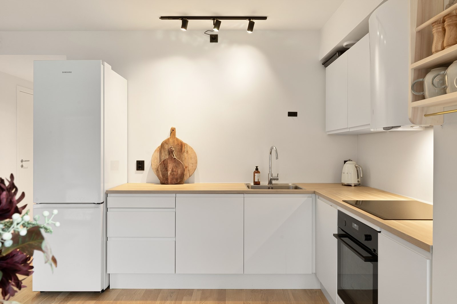 Moderne kjøkken med slette hvite fronter. Praktisk oppbevaring i skuffer og skap. Galleribilde