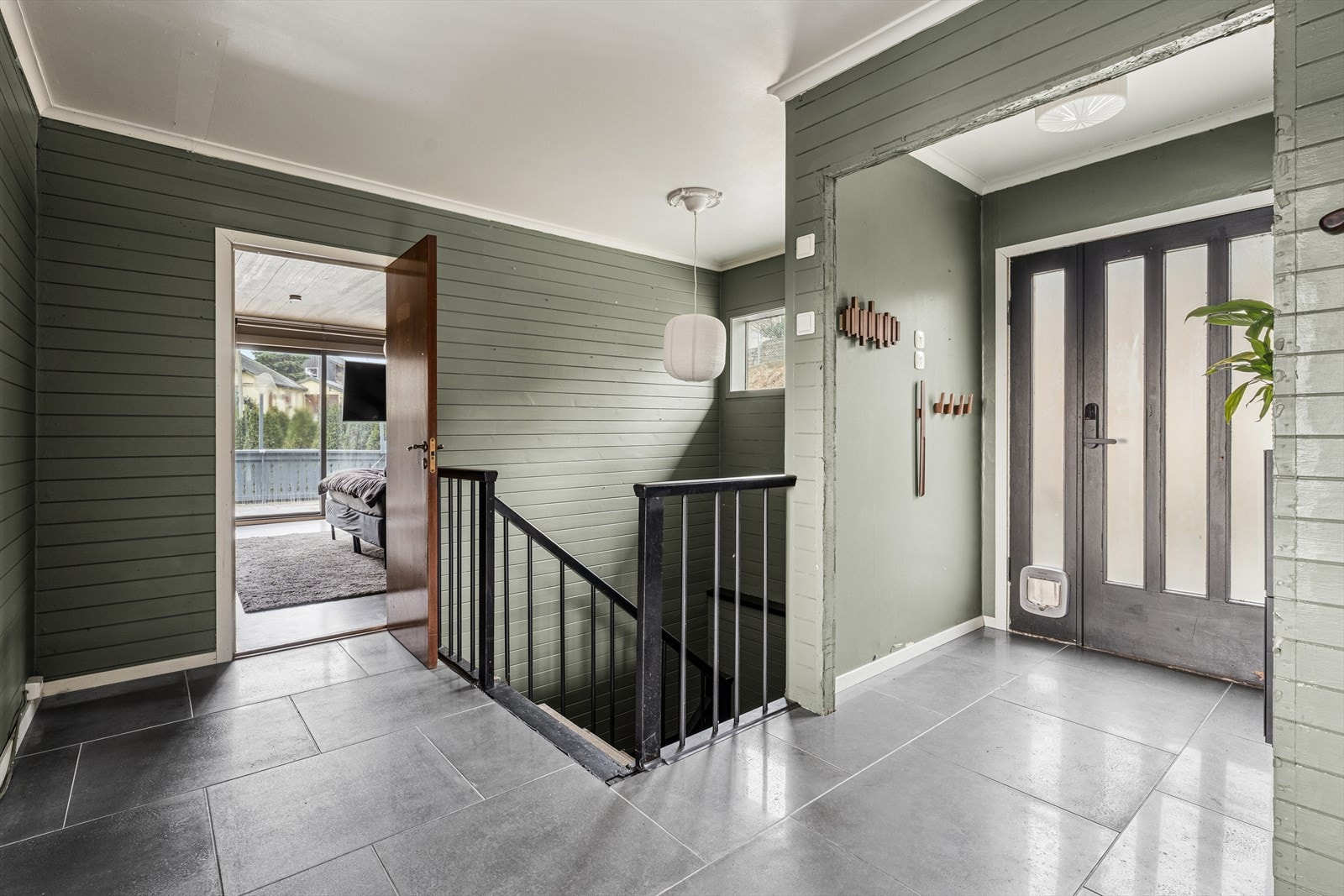 Velkommen inn i en romslig gang som er praktisk innredet med store, svarte fliser på gulvet. Galleribilde