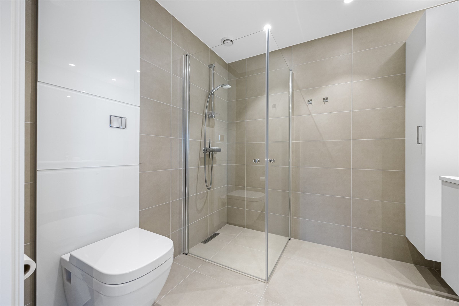 Baderommet er passe stort med vegghengt toalett, skap, servant, dusjhjørne og speil. Galleribilde