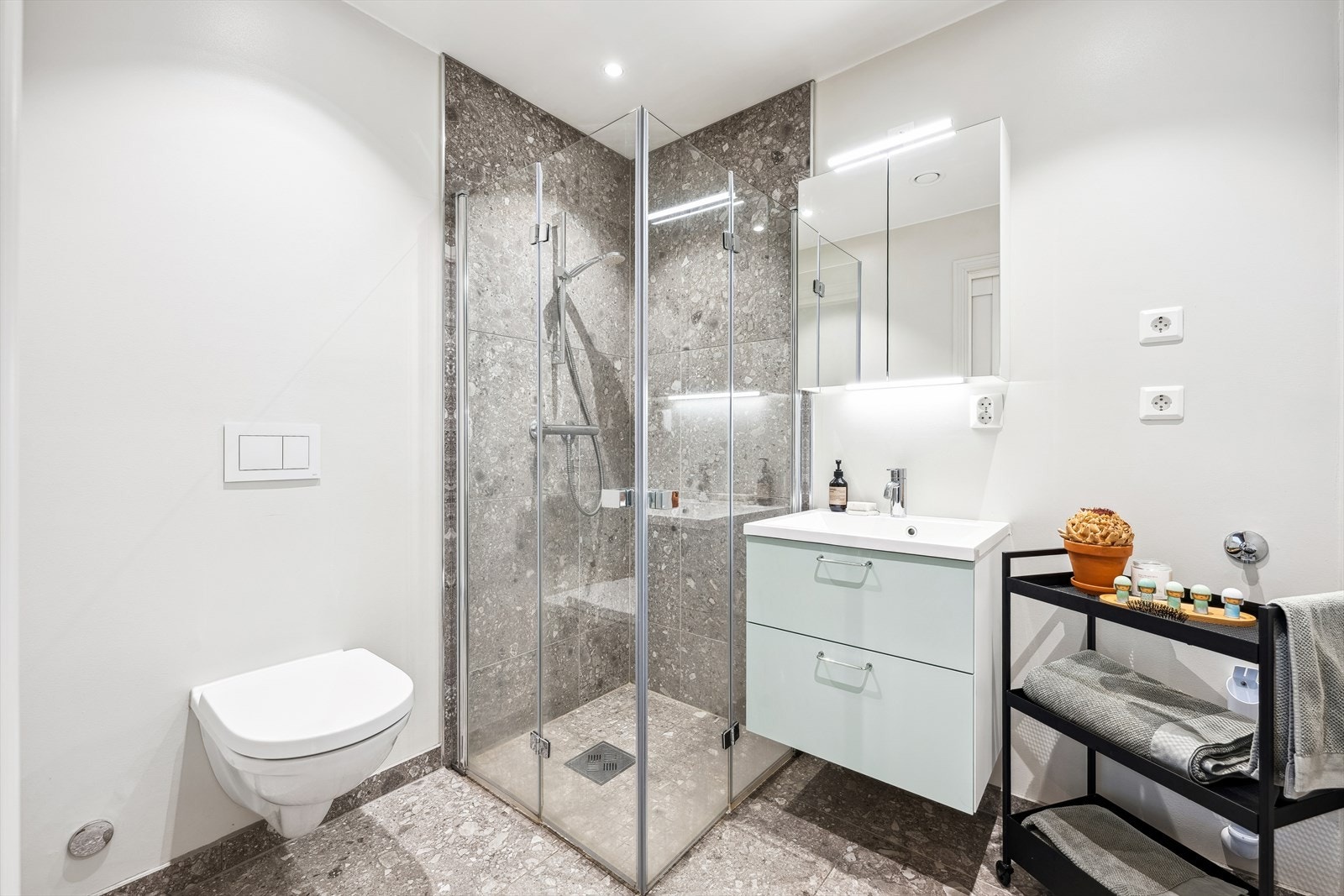 Lekkert bad med påkostede fliser. Badet har dusj med glassdører, vegghengt wc, innredning med vask og opplegg for vaskemaskin. Varmekabler i gulv. Galleribilde