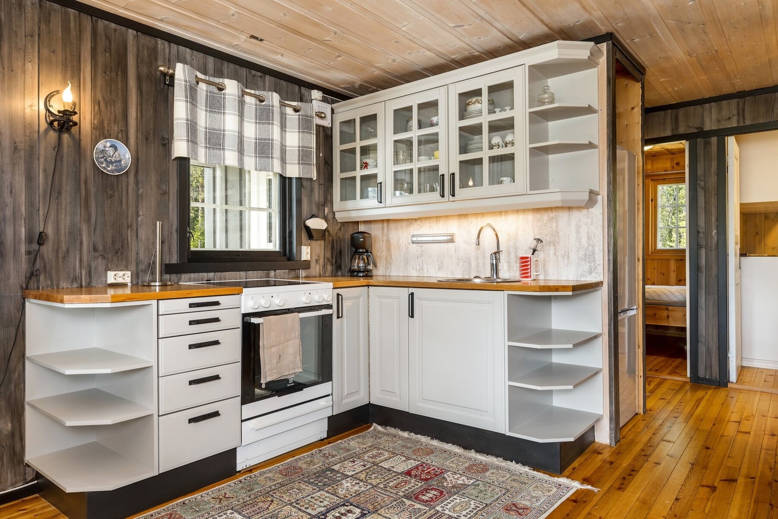 Kjøkken utstyrt med komfyr og oppvaskkum. Kjøleskapet er plassert til høyre for kjøkkenet. Galleribilde