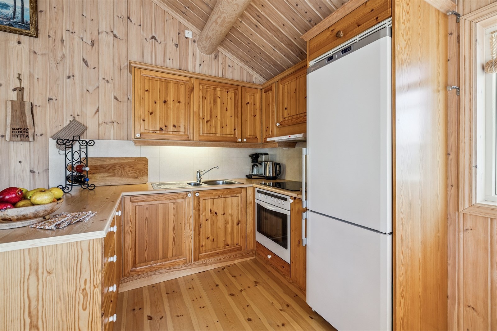 Kjøkkeninnredning i heltre furu med profilerte fronter og integrert stekeovn, koketopp og ventilator. Galleribilde