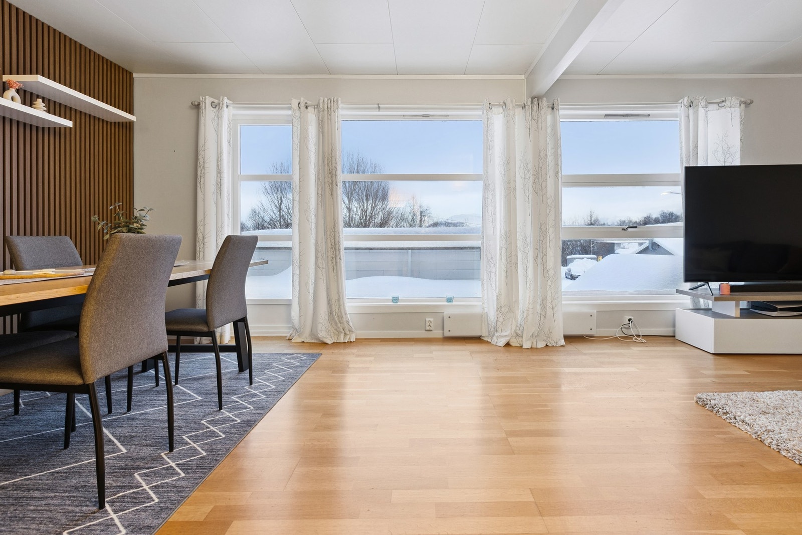 Romslig stue med store vinduer i front. Utgang til balkongen til venstre i bildet. Galleribilde