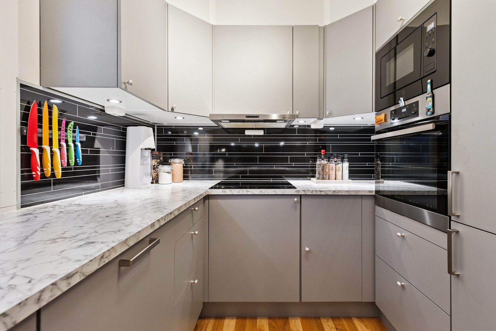 Kjøkkenet er i en moderne gråfarge, slette fronter og integrerte hvitevarer. Galleribilde