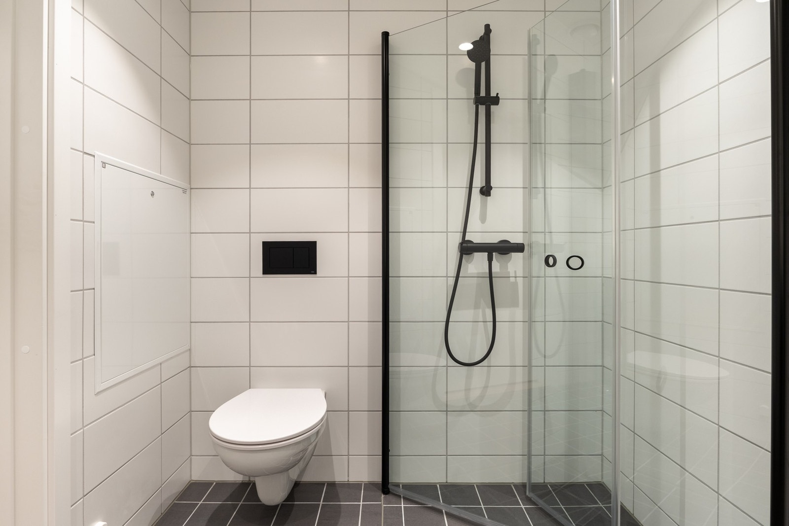 Romslig dusjhjørne og vegghengt toalett. Galleribilde