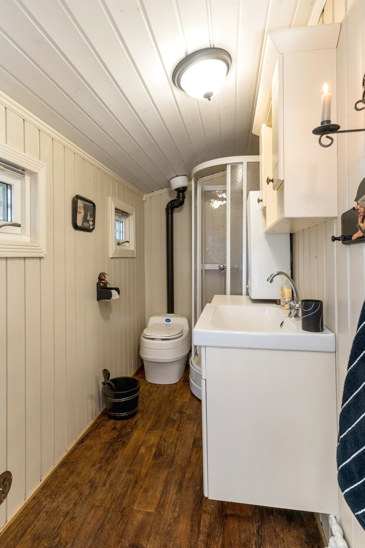 Enkelt hyttebad med servantskap, dusjkabinett og separett separasjonstoalett. Vannet pumpes med 12 volts pumpe til vask og dusj. Badet har varmtvannsbereder. Galleribilde