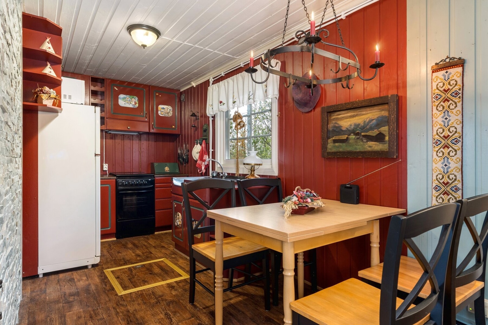 Trivelig hyttekjøkken utstyrt med komfyr og kombinert kjøl- og fryseskap. Vann pumpes med 12 volts pumpe fra kanne til vask. Galleribilde