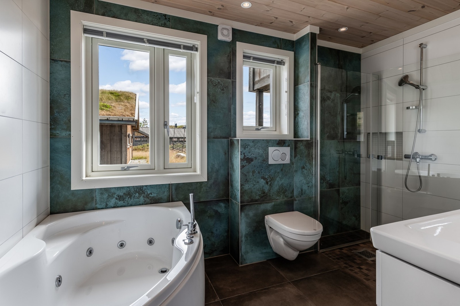 Flislagt bad innredet med dobbel servant, vegghengt toalett dusjhjørne og boblebad. Galleribilde