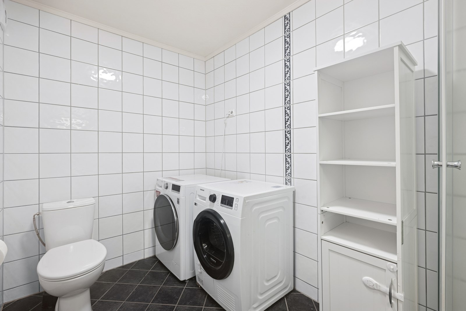 Badet er utstyrt med dusjkabinett, wc, opplegg for vaskemaskin/tørketrommel og lys baderomsinnredning. Galleribilde