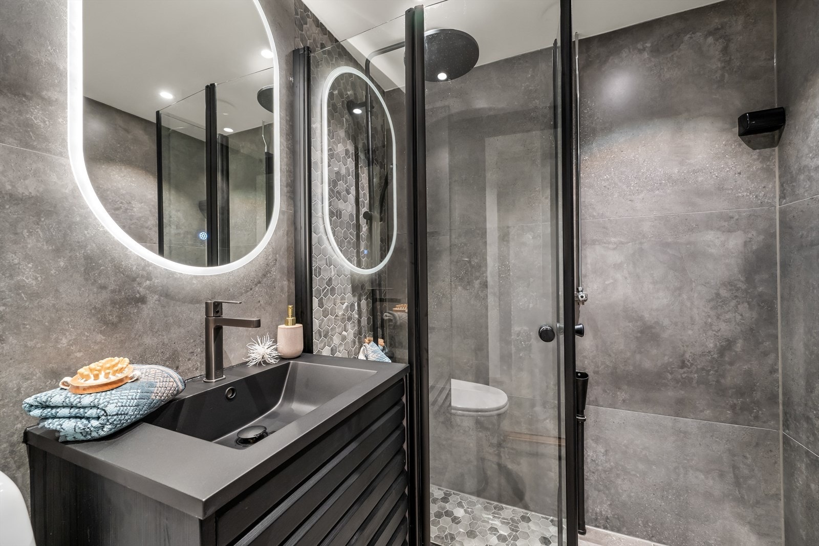 Stilrent og moderne bad med tidsriktige delikate fliser, varmekabler i gulv og en downlights i himling. Badet er fra 2025. Videre har badet dusj med dusjvegger med gjennomgående sorte detaljer Galleribilde