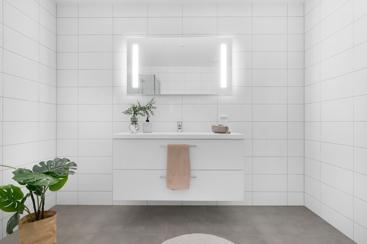 Moderne baderomsinnredning med god skuffeplass og overhengende speil Galleribilde