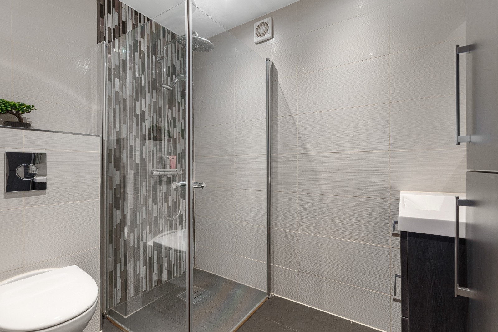 Det andre baderommet ligger i 2. etasje og ble også oppgradert i 2018. Rommet fremstår moderne og stilrent, med servant med slette fronter, veggmontert toalett og dusjhjørne med to svingbare glassdører, som gir både funksjonalitet og en elegant finish. Galleribilde