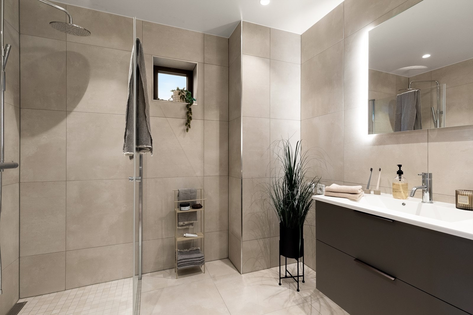 Badet tilknyttet gangen har samme delikate fliser på gulv og vegger som masterbadet, samt opplegg for vaskemaskin. Begge badene er plassbygde. Galleribilde