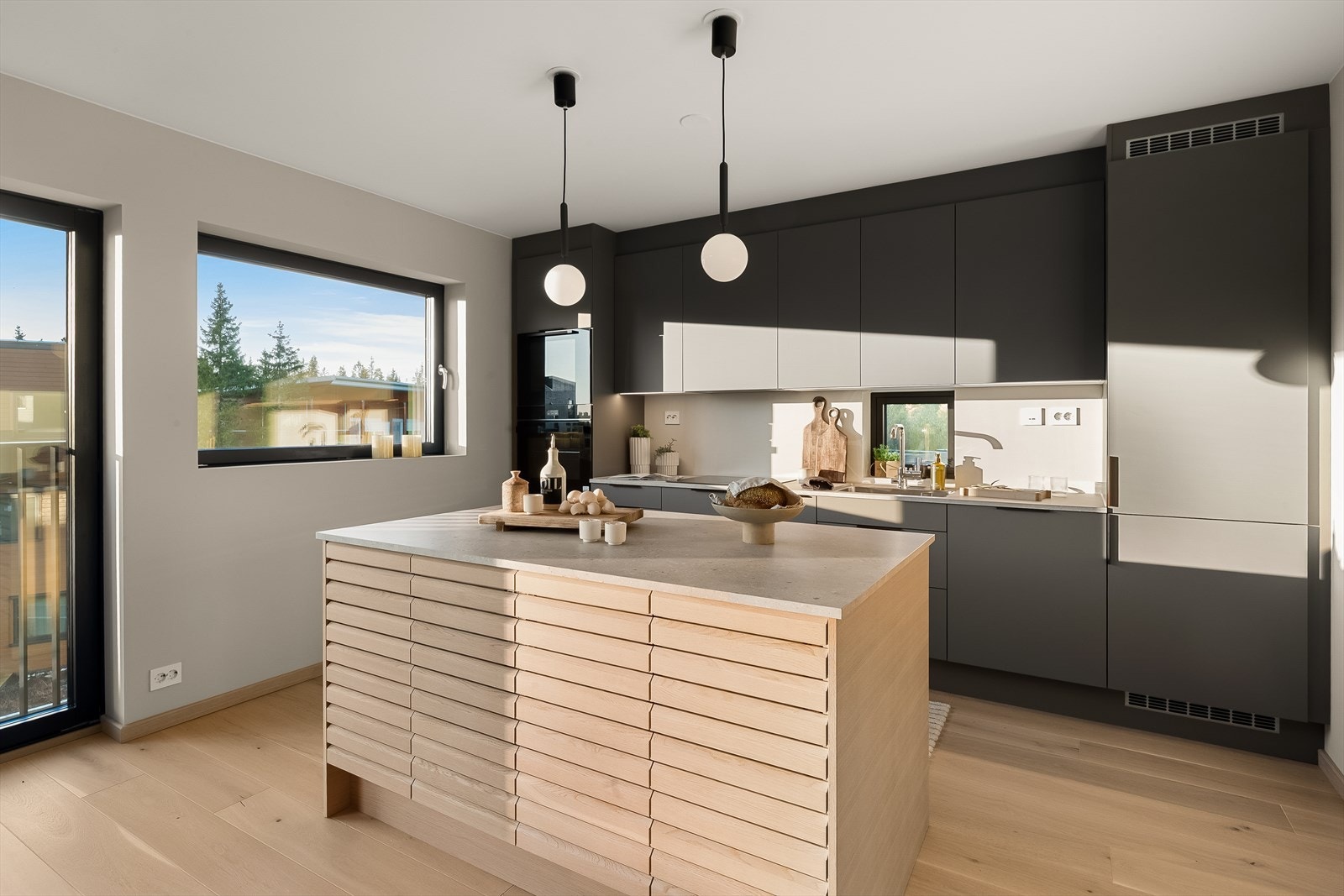 Innredningen langs veggen har takoppforede skap, matte fronter i fargen mørk sand og benkeplate med underlimt vaskekum. Galleribilde