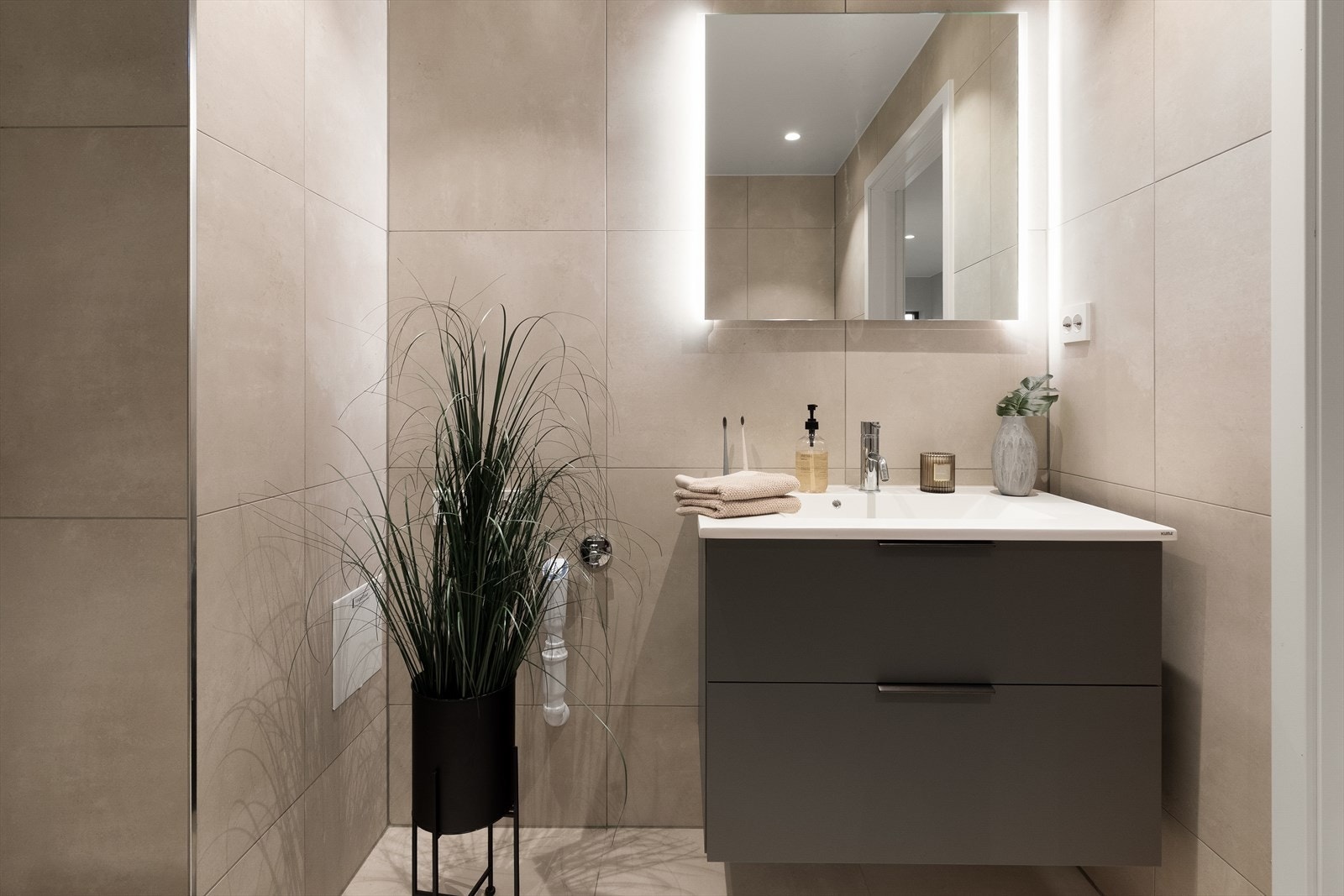 Badet med adkomst fra gangen har enkel servantinnredning, veggmontert toalett og dusjhjørne med regnfallsdusj. Galleribilde