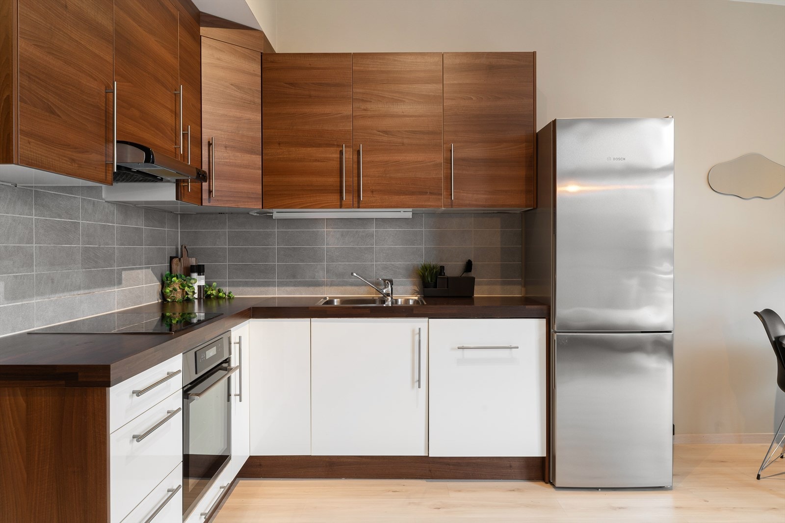 Fliser og god belysning over benk. Kjøkkenet har rikelig med skapplass, og hvitevarer som oppvaskmaskin og stekeovn er integrert. Galleribilde