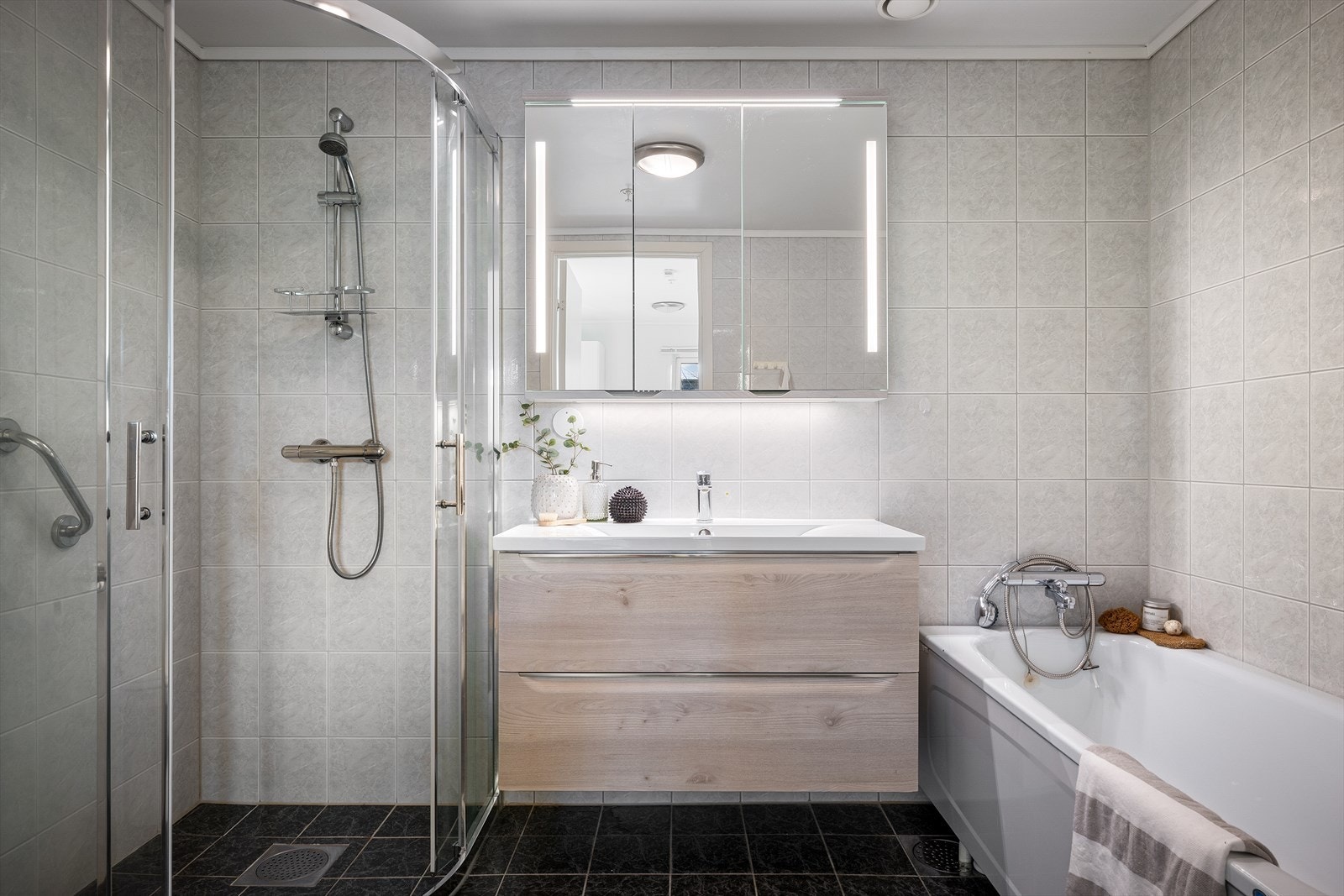 Pent hovedbad med fliser på gulv og vegg (varmekabler i gulv). Det er både dusjhjørne og badekar. Romslig baderomsinnredning Galleribilde