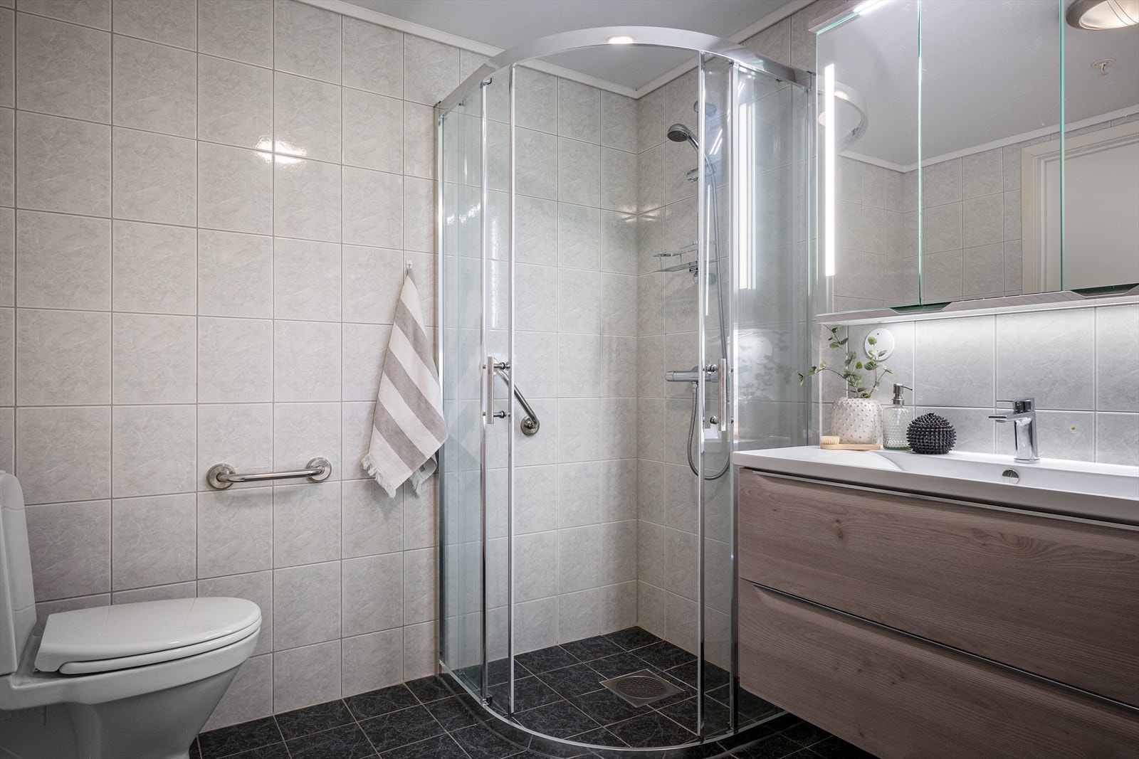 Pent hovedbad med fliser på gulv og vegg (varmekabler i gulv). Det er både dusjhjørne og badekar. Romslig baderomsinnredning Galleribilde